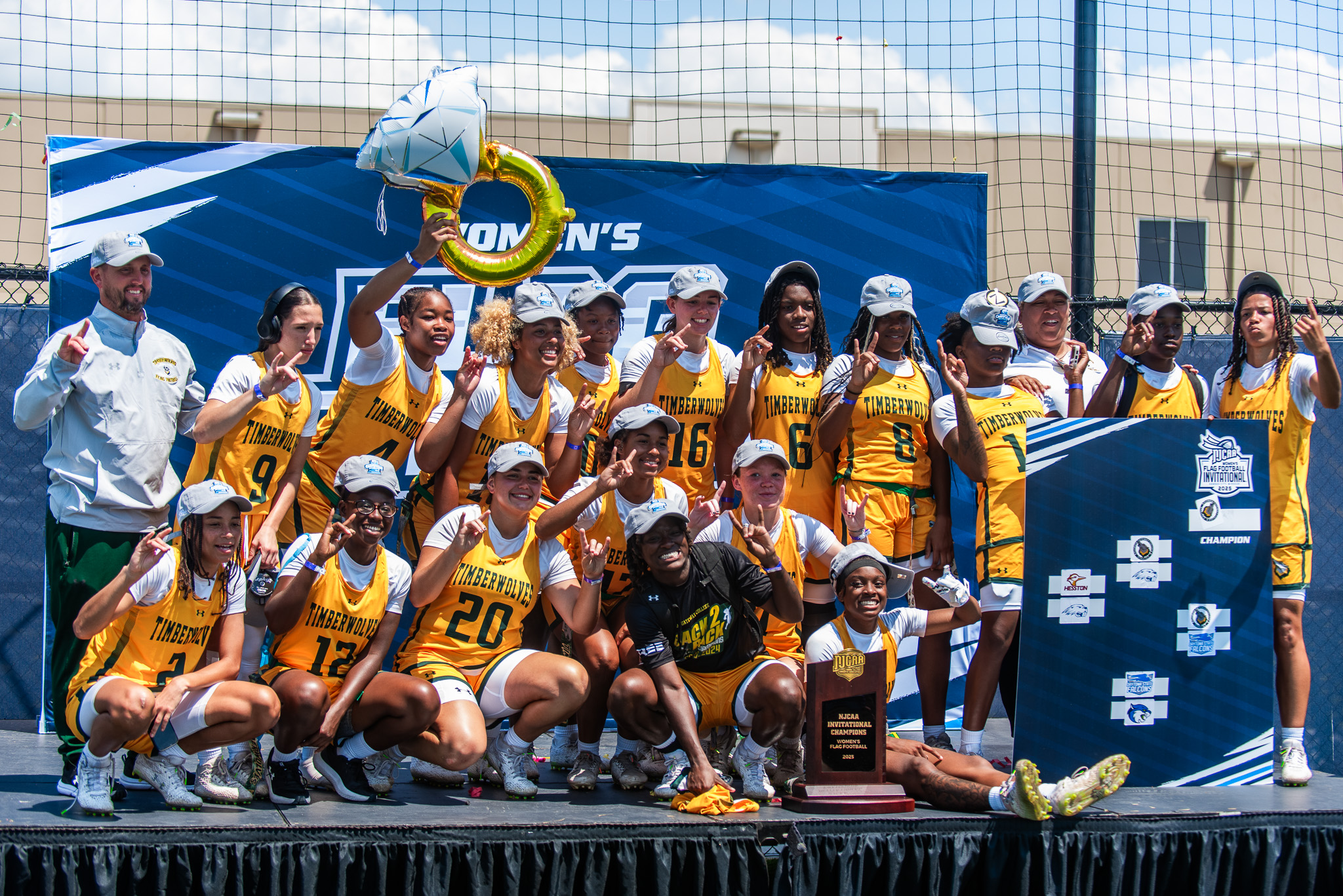 FGC Flag Football team celebrating championship win on stage with trophy.